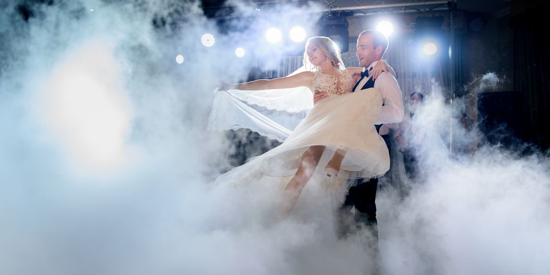 Groom whirls bride in the smoke dancing for the first time