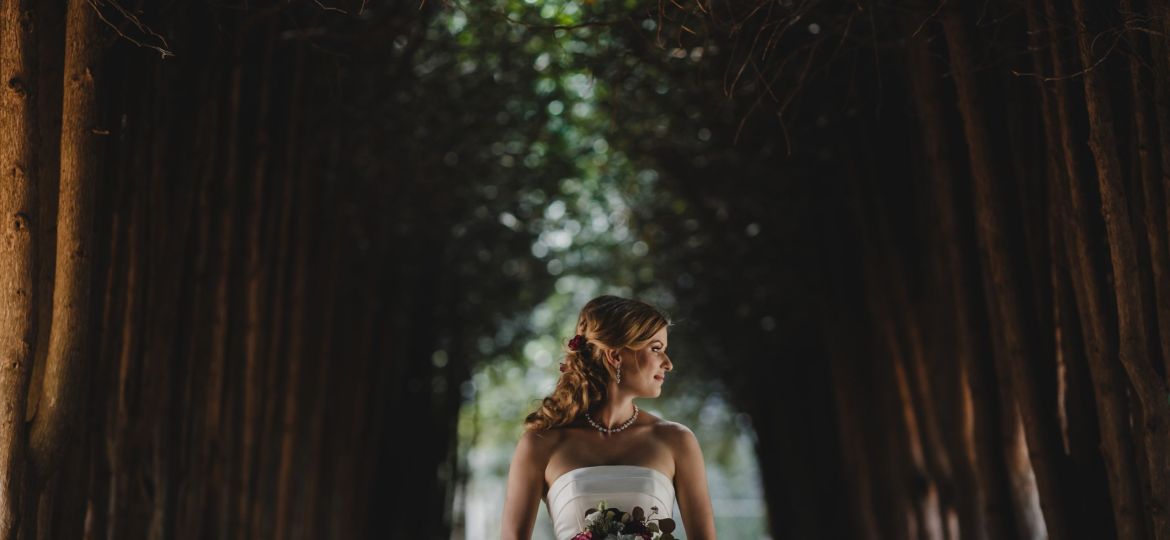 The beautiful bride with bouquet stands in the  park