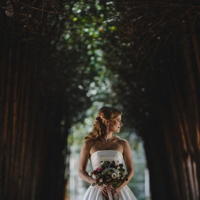 The beautiful bride with bouquet stands in the  park